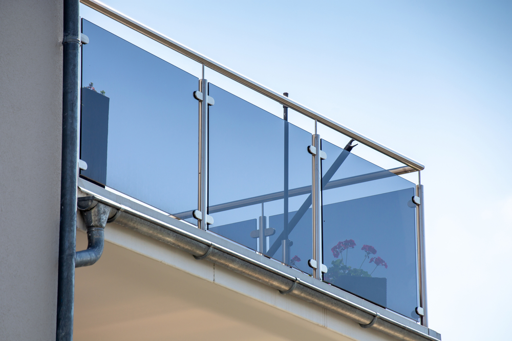 New,Modern,Glass,Balcony,Railing Modern balcony railing featuring dark tinted glass panels and steel supports.