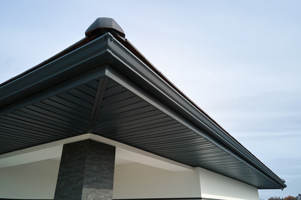 House,Corner,With,Brown,Metal,Planks,Siding,And,Roof,With Dark house roof overhang with soffit ventilation and guttering.