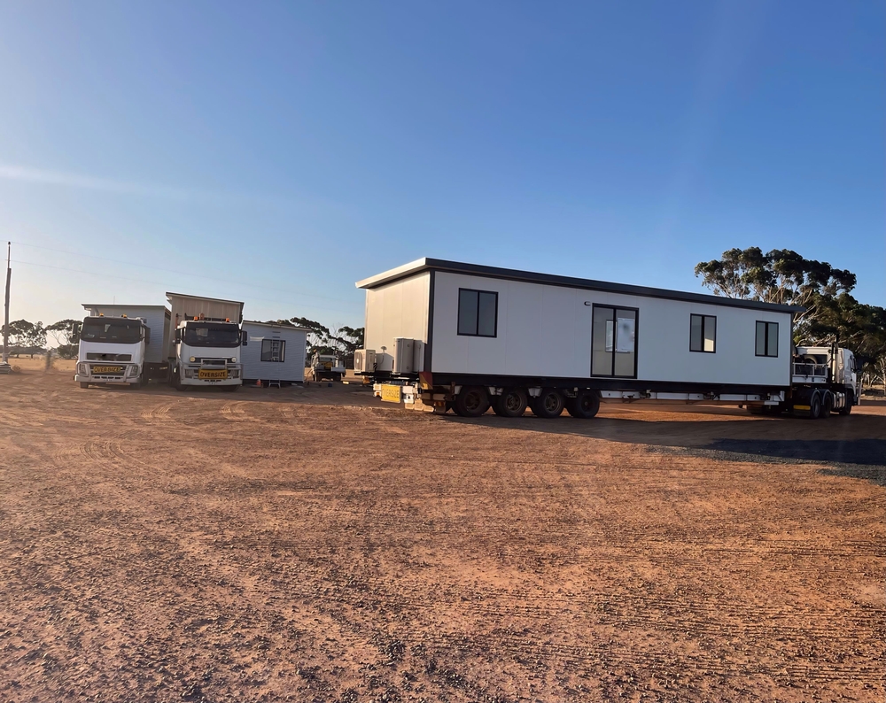 Portable,Dongas,(modular,Transportable,Building).,Amazing,Sunset.,Waterholes.,Australia. Modular prefabricated building parked outdoors beside trucks.